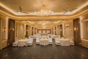 兰纳加Wood castle Spa & Resort的宴会厅配有白色桌子和吊灯