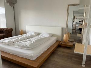 温特图尔goodstay的一张带白色床单和镜子的睡床