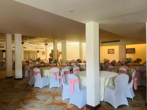 阿鲁特伽马Muthumuni Ayurveda River Resort的宴会厅配有桌椅和粉红色的弓