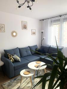 格但斯克sunset apartament的客厅配有蓝色的沙发和2张桌子