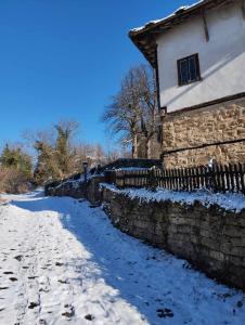 波兹思Расимова къща的石头建筑旁边的一条有雪覆盖的街道
