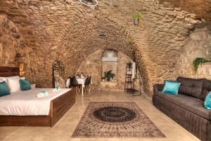 萨法德קשתות - מתחם אבן בצפת העתיקה - Kshatot - Stone Complex in Old Tzfat的一间石墙内配有沙发和桌子的房间