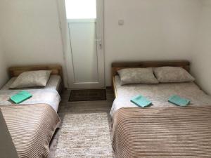 莫伊科瓦茨Private accommodation Kalezić的小客房内的两张床和绿色枕头