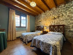 LuzmelaCasa Rural La Socarrena的一间卧室设有两张床和石墙
