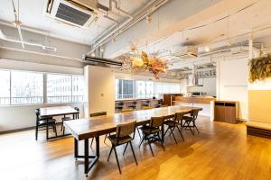 大阪Hostel OGK的大型用餐室配有长桌和椅子