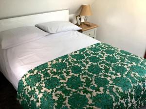 灵伍德Selfcatering Coach House New Forest Dog Friendly的床上铺有绿色和白色的毯子