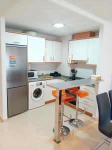 甘迪亚Apartamento Luna的厨房配有白色橱柜、桌子和洗碗机。