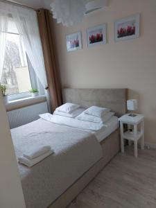 绿山城come&stay Zielona Góra的卧室配有白色的床和窗户。