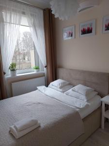 绿山城come&stay Zielona Góra的一间卧室配有一张带白色床单的床和一扇窗户。