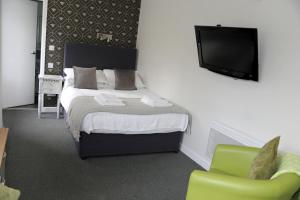 曼彻斯特公牛头酒店的一间卧室配有一张床、一台电视和一把椅子