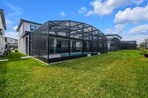 奥兰多Orlando's Best Escape Residence at Paradiso Grande Resort home的一座玻璃房子,在院子里设有游泳池