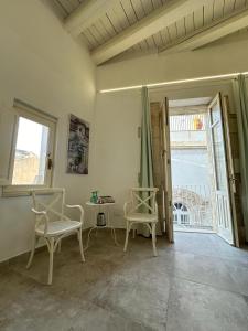 锡拉库扎Archè的一间设有两把椅子、一张桌子和一个窗户的房间