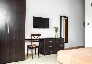 MaturínHotel Kariña Maturín的一间卧室配有一张桌子、一台电视和一把椅子