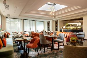 巴黎Hotel Etoile Maillot的餐厅设有橙色椅子和桌子以及窗户。