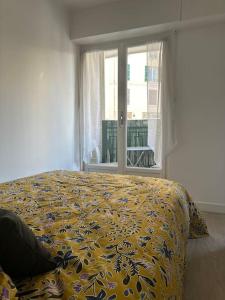 戛纳Joli F2, 7 min de la gare的一间卧室配有一张带黄色棉被的床和窗户