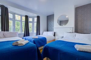 伦敦Streatham Hotel的一间卧室配有两张带蓝色床单和镜子的床