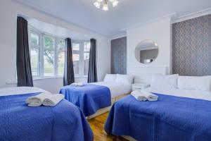 伦敦Streatham Hotel的一间卧室配有三张床、蓝色床单和镜子