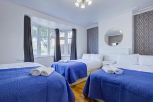 伦敦Streatham Hotel的酒店客房,配有三张带蓝色床单的床