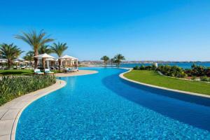 赫尔格达萨尔哈氏男爵宫殿度假村的拥有蓝水和棕榈树的度假村的游泳池