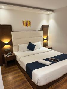 孟买Hotel the pacific Chakala的一间卧室配有一张带两盏灯的大型白色床。