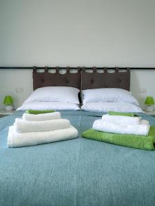 坎波巴索Puzzle Rooms的一张带白色枕头和绿色毛巾的床