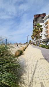 格勒姆YULIA apartment的海滨人行道,旁边是棕榈树海滩和一座建筑