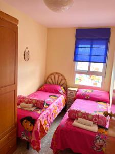 卡耐特蒂贝兰格Apartamento en la Playa Canet, muy cerca de Valencia的一间卧室设有两张带粉色床单的床和窗户。