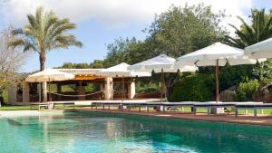 圣洛伦索巴拉菲Agroturismo Can Gall的游泳池旁设有桌子和遮阳伞的游泳池