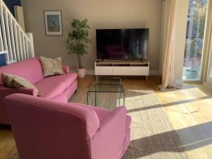 HubyTime House Cottage的客厅配有2张粉红色的沙发和电视