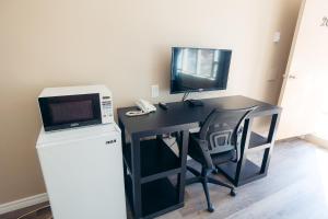 米西索加克拉克森村汽车旅馆 的一张黑色的书桌,配有微波炉和电视