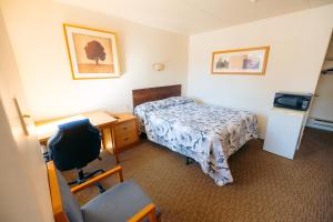 米西索加克拉克森村汽车旅馆 的酒店客房配有一张床、一张桌子和一把椅子。