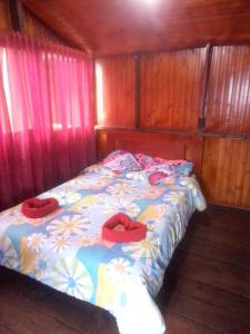 阿基塔尼亚Madervillhospedaje的一间卧室配有一张带两个红色枕头的床