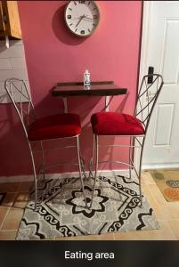 马尔斯港SanAndros Airbnb的一张桌子,两把椅子和墙上的时钟