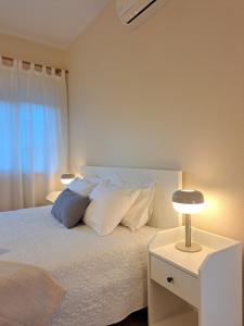 波尔蒂芒Villa Prana Guesthouse, Yoga & Ayurveda的一间卧室配有带白色床单和枕头的床。