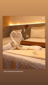 卡皮托利乌Paraíso Capitólio Suítes Pousada的酒店客房,配有两张带心形毛巾的床