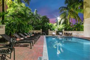 劳德代尔堡Hyatt Place Fort Lauderdale Cruise Port & Convention Center的一个带黑色躺椅的游泳池,棕榈树