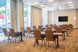 西棕榈滩西座落滩凯悦普雷斯酒店的一间会议室,配有桌椅和平面电视