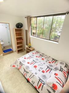 麦德林23 COMODO APARTAMENTO CON BALCON EN LAURELES ESTADiO 2 HAB 2 BAÑOs的一间卧室配有一张带床罩的床和窗户