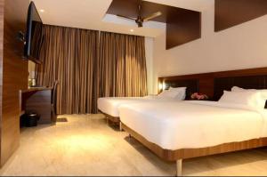 拉马纳塔普拉姆NESTLAYROOMS RAMNAD的酒店客房设有两张床和电视。
