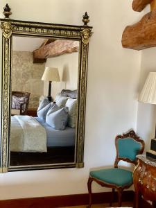 FougueyrollesChateau Masburel的卧室内的镜子,配有一张床和椅子