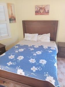EslabónHotel V. Maria的一张带蓝色床单的床,上面有白色的花朵
