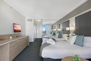 黄金海岸Cosy 2-Bed Central Studio Apartment With Views的酒店客房设有三张床和电视。