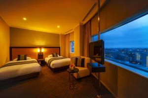 埼玉市大宫皇宫酒店(Palace Hotel Omiya)的酒店客房设有两张床和大窗户。