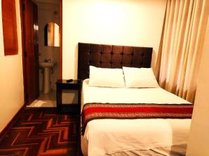 库斯科Paqarina San Blas的一间卧室配有一张带棕色床头板的床