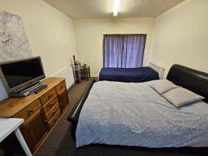 阿什顿下安林恩2 bedroom apartment in Greater Manchester的一间卧室配有一张床和一台平面电视