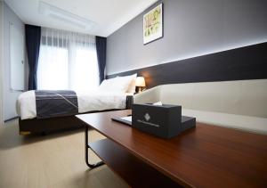 束草市Sokcho Chonpines Beach Hotel的一间卧室配有一张床和一张带笔记本电脑的书桌