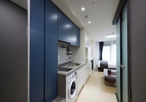 束草市Sokcho Chonpines Beach Hotel的厨房配有蓝色橱柜、洗衣机和烘干机
