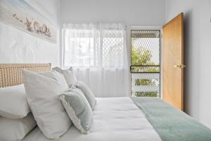 穆卢拉巴Chic 2-Bed Cabin-Style Home by Mooloolaba Beach的卧室配有带白色枕头的床和窗户。