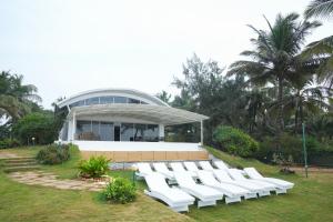 比纳里姆Beach House Resort Goa的建筑前的一组白色椅子
