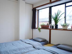 神户KOBE coffee hostel的一间卧室设有床铺和植物窗户